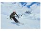 Un skieur descendant une pente enneigée dans les montagnes.