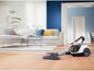 Un aspirateur Philips sur un sol en bois dans un salon.