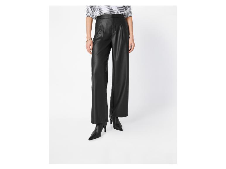 Femme en chemise rayée, pantalon en cuir noir et bottes noires à talons.