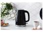Une bouilloire Russell Hobbs noire à motif nid d'abeille sur un comptoir en marbre.