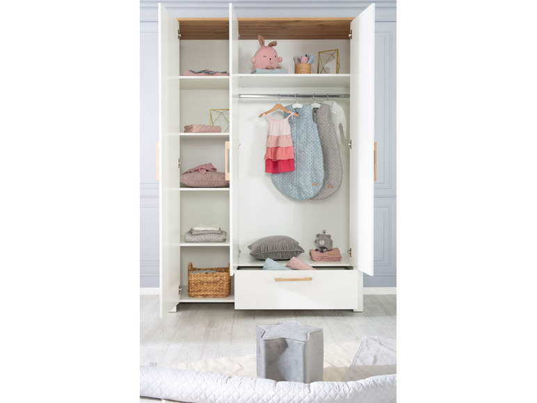 Une armoire blanche avec des gigoteuses, des peluches et un panier