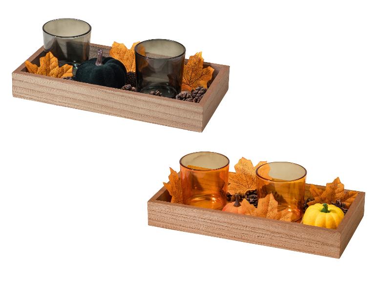 Plateau en bois automnal avec bougeoirs en verre, citrouilles décoratives, feuilles et pommes de pin.