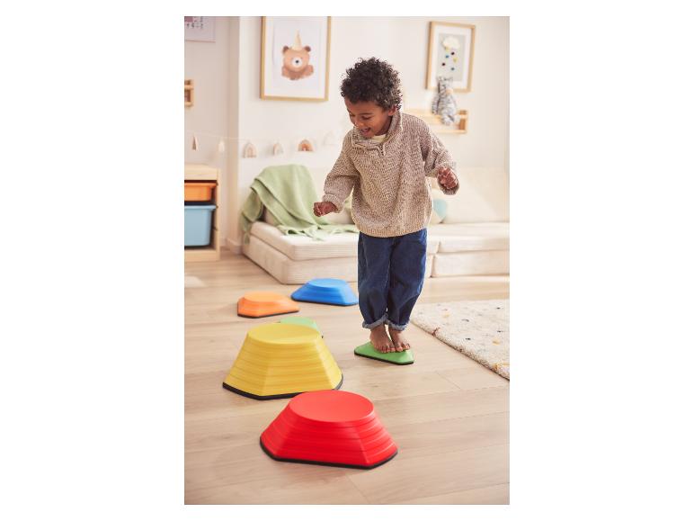 Enfant heureux jouant avec des pas colorés sur un sol en bois.