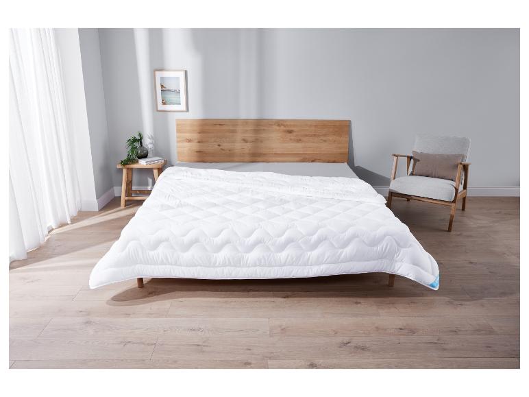 Couette blanche sur un cadre de lit en bois dans une chambre à coucher.