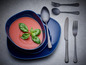 Soupe de tomates dans un bol bleu avec des couverts noirs