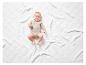 Un bébé dans un body blanc avec un imprimé girafe sur une couverture blanche.