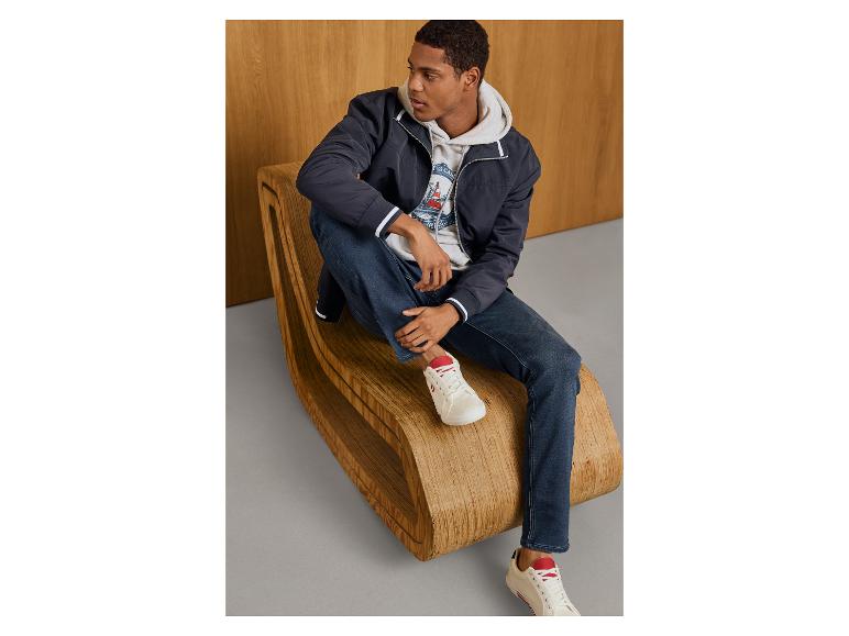 Homme en sweat à capuche ESMARA MEN, veste bleue et jean sur un banc en bois.