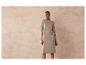 Une femme porte une robe en tricot beige avec une ceinture.