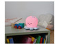 Une lampe de chevet en forme de poulpe rose sur une table de chevet avec des livres et des jouets.