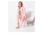 Femme en sweat à capuche rose et pantalon assorti assise sur une chaise blanche.
