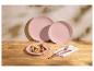 Assiettes rose pastel avec crêpes aux fruits et couverts en cuivre sur une table en bois.