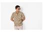 Homme en polo à motif feuilles et short clair, portant des lunettes de soleil