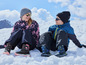Deux enfants en vêtements d'hiver assis dans la neige