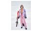 Fille souriante en tenue de ski rose et fleurie, avec skis et bâtons.