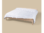 Couette blanche matelassée avec motif sur un lit en bois.
