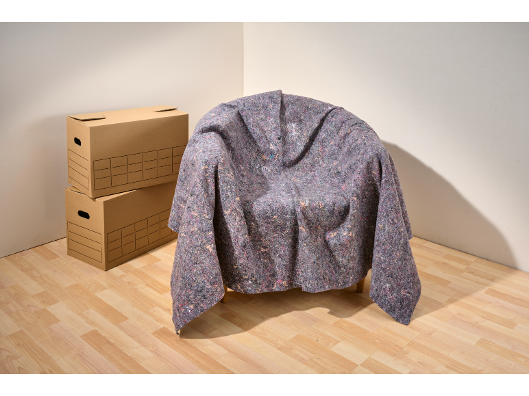 Un fauteuil recouvert d'une housse de protection, à côté de cartons.