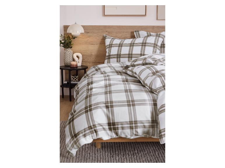 Chambre avec literie à carreaux, tête de lit en bois et table de chevet avec décorations.