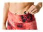 Une femme range une clé dans la poche de son legging rouge à motifs.