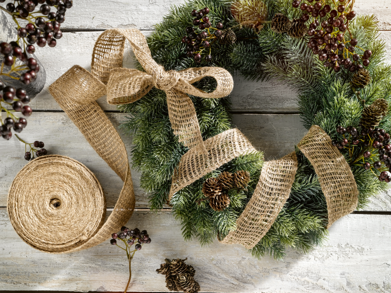 Couronne de Noël avec ruban de jute et baies sur fond de bois blanc.