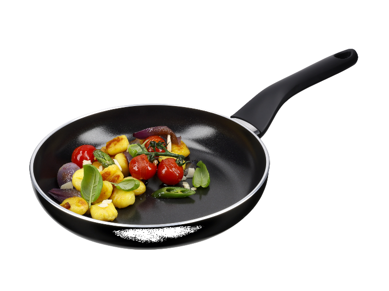Une poêle noire avec des gnocchis, des tomates et des oignons.
