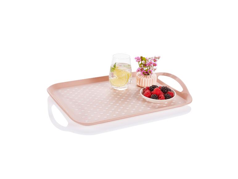 Plateau rectangulaire rose à pois blancs avec des fruits rouges, un verre et un vase.