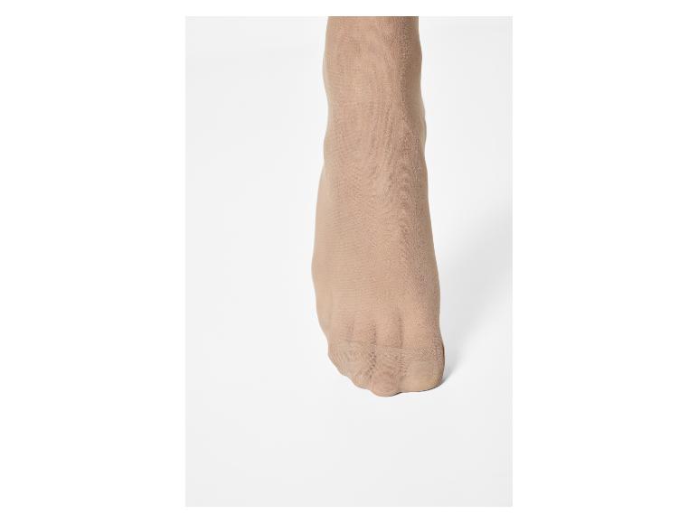 Pied de femme avec des collants couleur chair sur fond blanc.