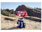 Un jouet Optimus Prime se tient sur un terrain rocheux et sablonneux sous un ciel clair.