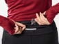 Gros plan sur une personne mettant une clé dans la poche zippée d'un pantalon de sport noir.