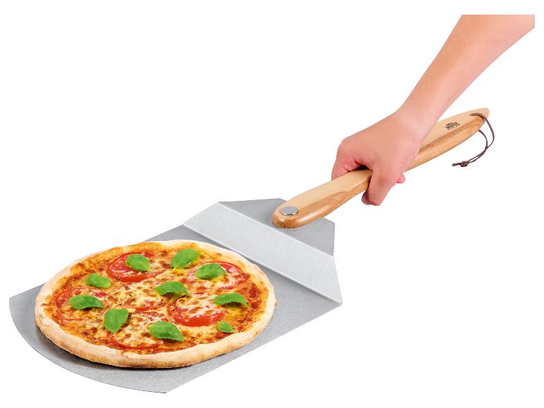 Main tenant une pelle à pizza avec une pizza Margherita fraîchement cuite.