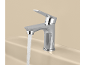 Robinet chromé avec de l'eau qui coule dans un lavabo beige