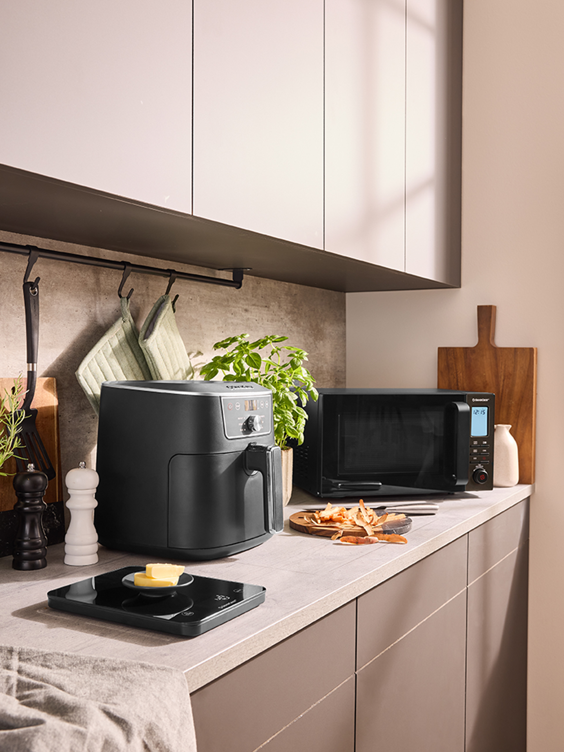 Une friteuse à air et un micro-ondes sur un comptoir de cuisine moderne.