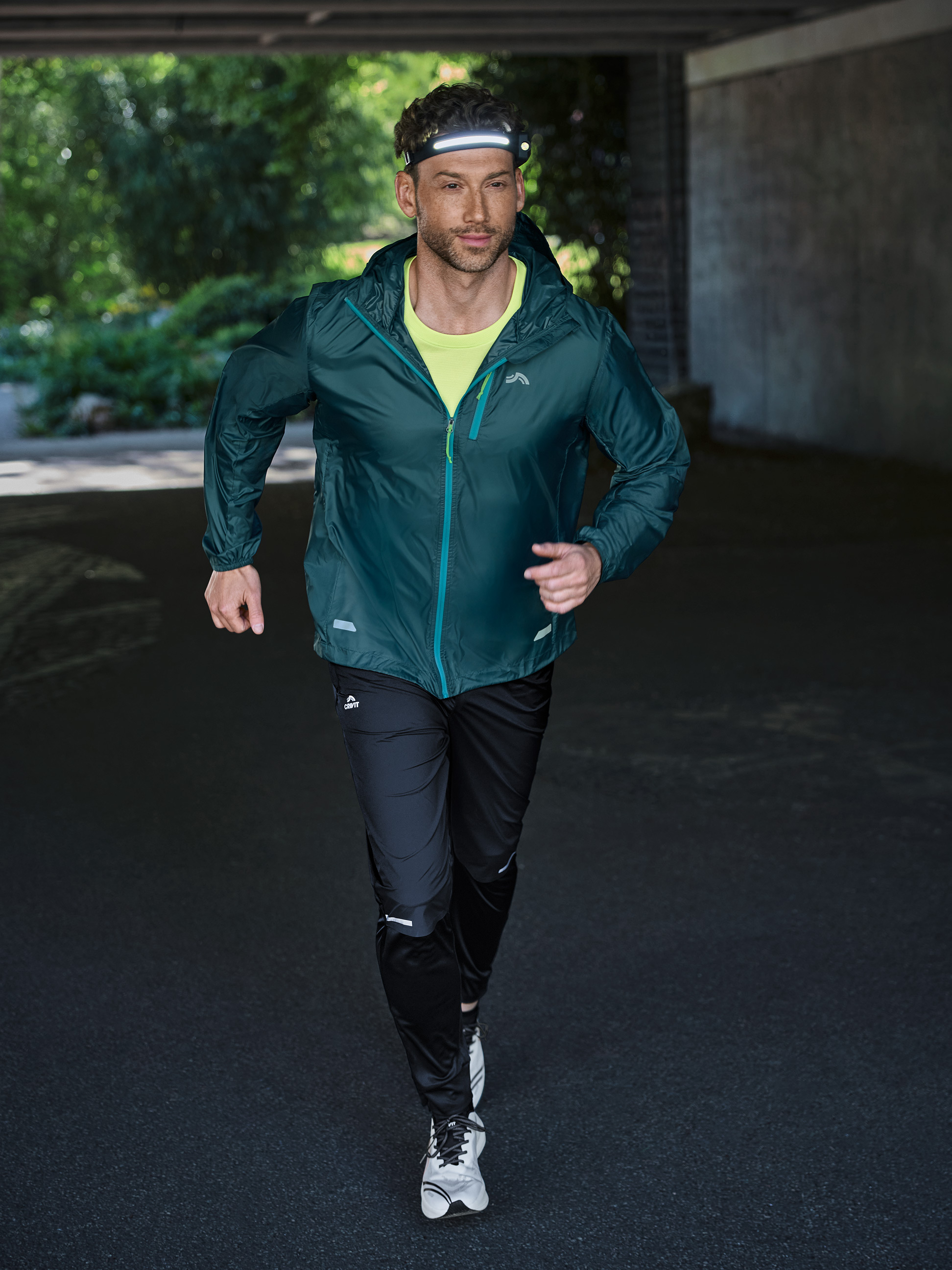 Homme courant en tenue de sport avec une lampe frontale dans un tunnel