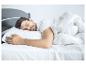 Un homme dort dans un lit avec une couette et un oreiller blancs.