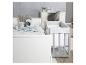 Chambre d'enfant avec un lit blanc, un berceau gris et un bureau avec une lampe 'LITTLE STAR'.