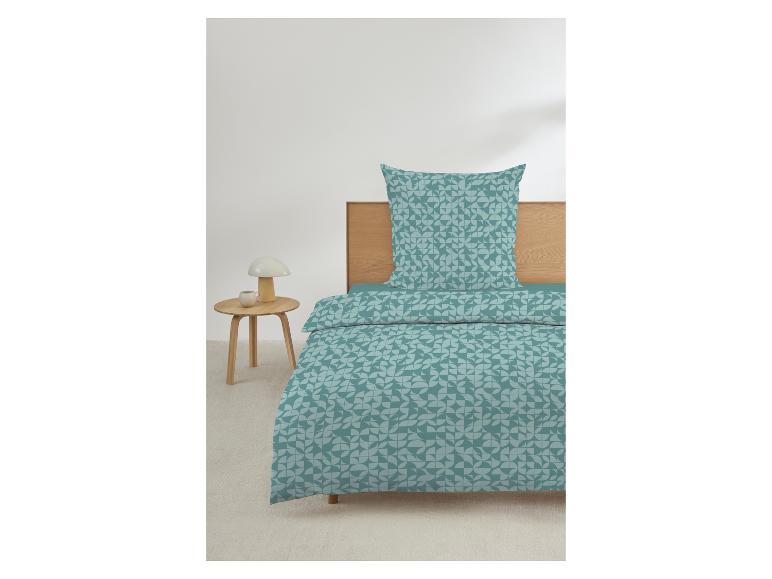 Housse de couette et taie d'oreiller à motif géométrique turquoise et gris, sur un lit avec tête de lit en bois.