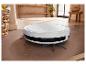 Robot aspirateur blanc nettoyant un sol.