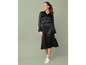 Une femme portant une robe noire en satin avec des baskets blanches.