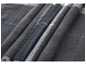 Gros plan sur une couverture douce pliée avec un motif à carreaux gris et bleus.