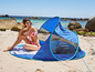 Une femme en bikini se détend dans un abri solaire bleu Livarno sur la plage.