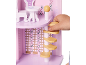 Main d'enfant jouant avec une maison de poupée en bois rose, avec meubles et escalier en colimaçon.