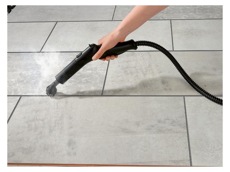 Main tenant un nettoyeur vapeur, nettoyant des carreaux de sol gris clair à la vapeur