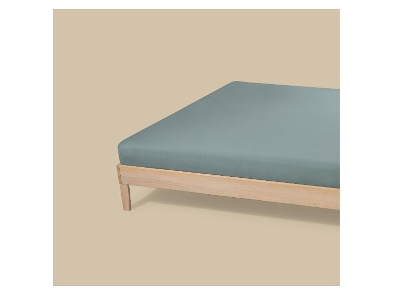 Lit avec cadre en bois et drap-housse bleu-vert.