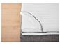 Matelas blanc avec fermeture éclair sur un sommier de lit gris.