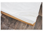 Un matelas blanc avec une fermeture éclair, sur un cadre en bois, sur un sol en bois.