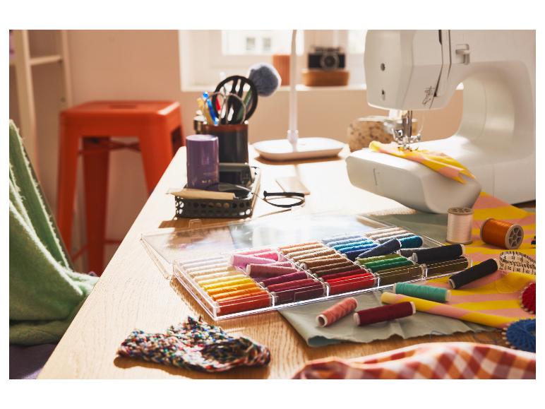 Un bureau avec une machine à coudre, des fils de couleurs et des outils de couture.