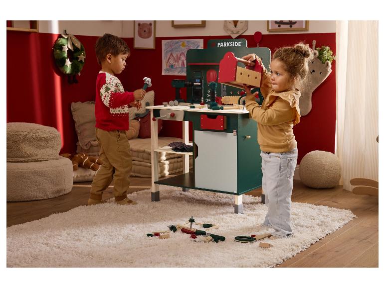 Deux enfants jouent avec un établi jouet Parkside et des outils.