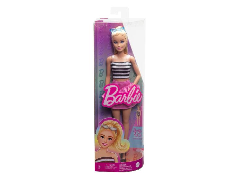 Poupée Barbie dans son emballage, vêtue d'un haut blanc et noir et d'une jupe rose.