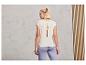 Une femme porte un t-shirt blanc avec un dos ouvert et un pantalon bleu clair.