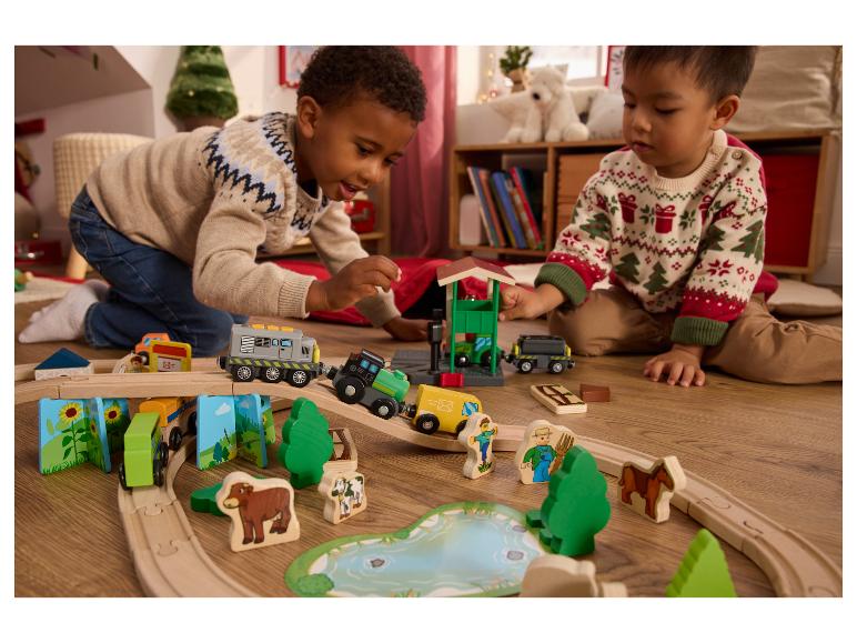 Deux enfants jouent avec un train en bois et un ensemble de ferme.