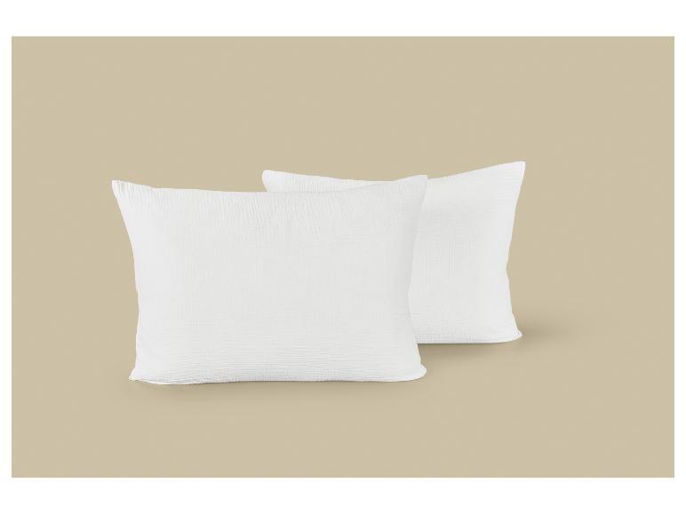 Deux oreillers blancs texturés sur un fond beige